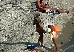 Couple baise sur une plage publique, tout en passant devant les gens